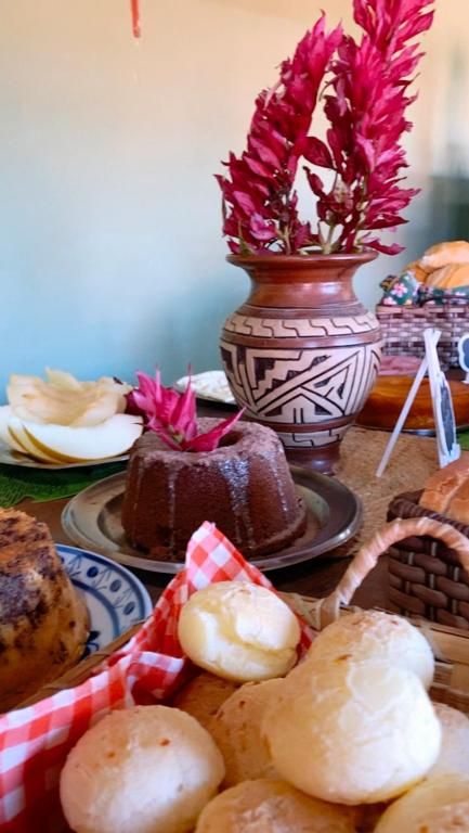 Bolo de chocolate, pão de queijo e flores em vaso de cerâmica